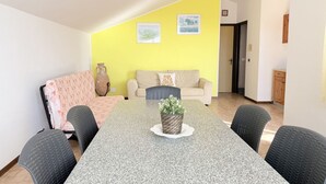 A dining area with a granite table, four chairs, a sofa, and a yellow accent wall. - M470 - Marcelli, three-room apartment with sea view (Marcelli)