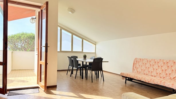 A room with a dining table and chairs, a sofa, and a large window. - M470 - Marcelli, three-room apartment with sea view (Marcelli)