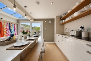 Una cucina moderna con un'ampia finestra, scaffali in legno e un'area pranzo con vista.