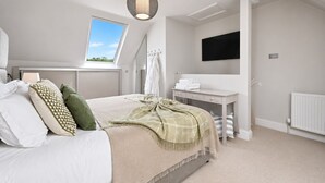 A bedroom with a bed, a desk, a TV, a window, and a skylight. - Hydrangea House -  a managed house that sleeps 10 guests  in 4 bedrooms (Hythe)