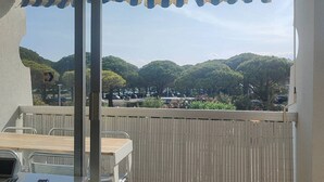 Varanda com mesa e cadeiras, um laptop e vista para uma área arborizada.