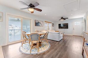 A modern living room with a dining area, a sofa, a TV, and a ceiling fan. - Cozy Coastal Luxury Home w/ Dock + Panoramic Views (Stafford Township)