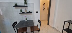 A small dining area with a table, chairs, and potted plants on shelves. - Tranquility and Comfort near Trastevere (Roma)