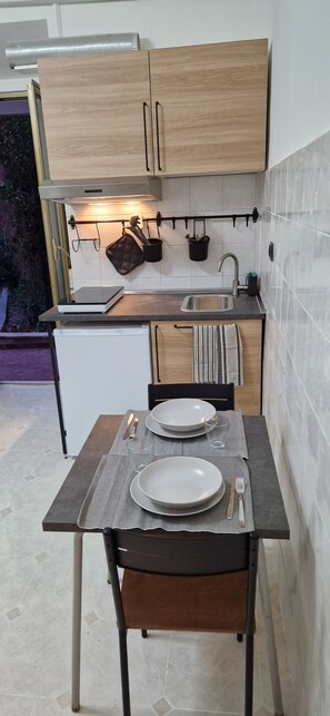 A compact kitchen with wooden cabinets, a countertop, and a dining area set with plates, cutlery, and a glass. - Tranquility and Comfort near Trastevere (Roma)