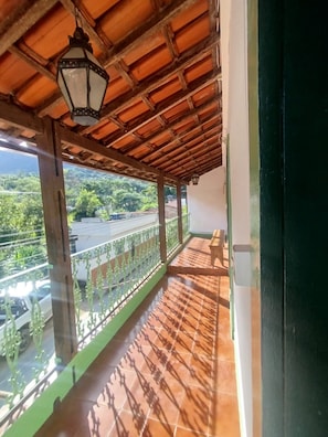 Een balkon met betegelde vloer, houten plafond en een hangende lantaarn.