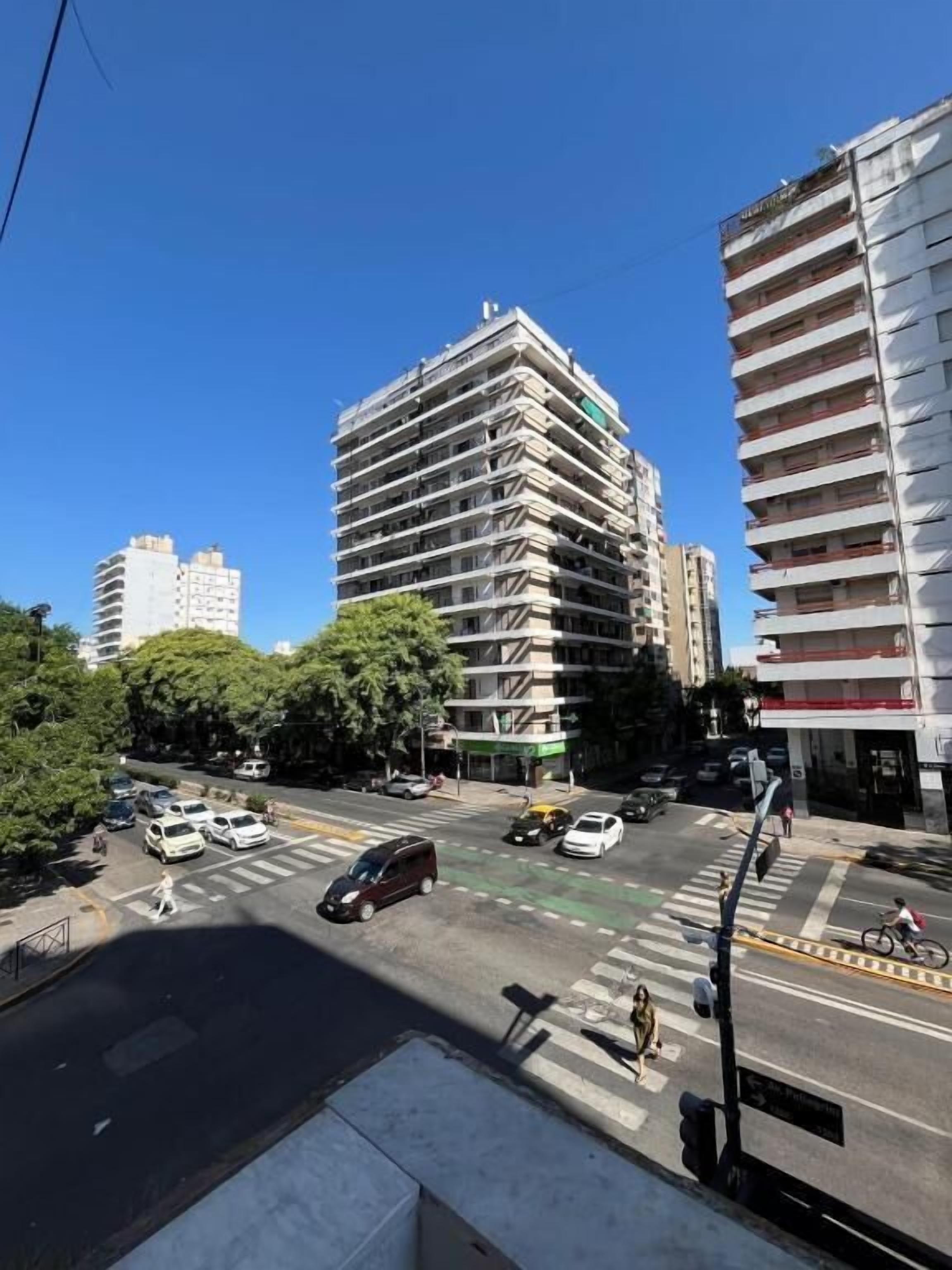 Un edificio de varios pisos con un diseño arquitectónico moderno, que destaca por su estructura en esquina y fachada plana.