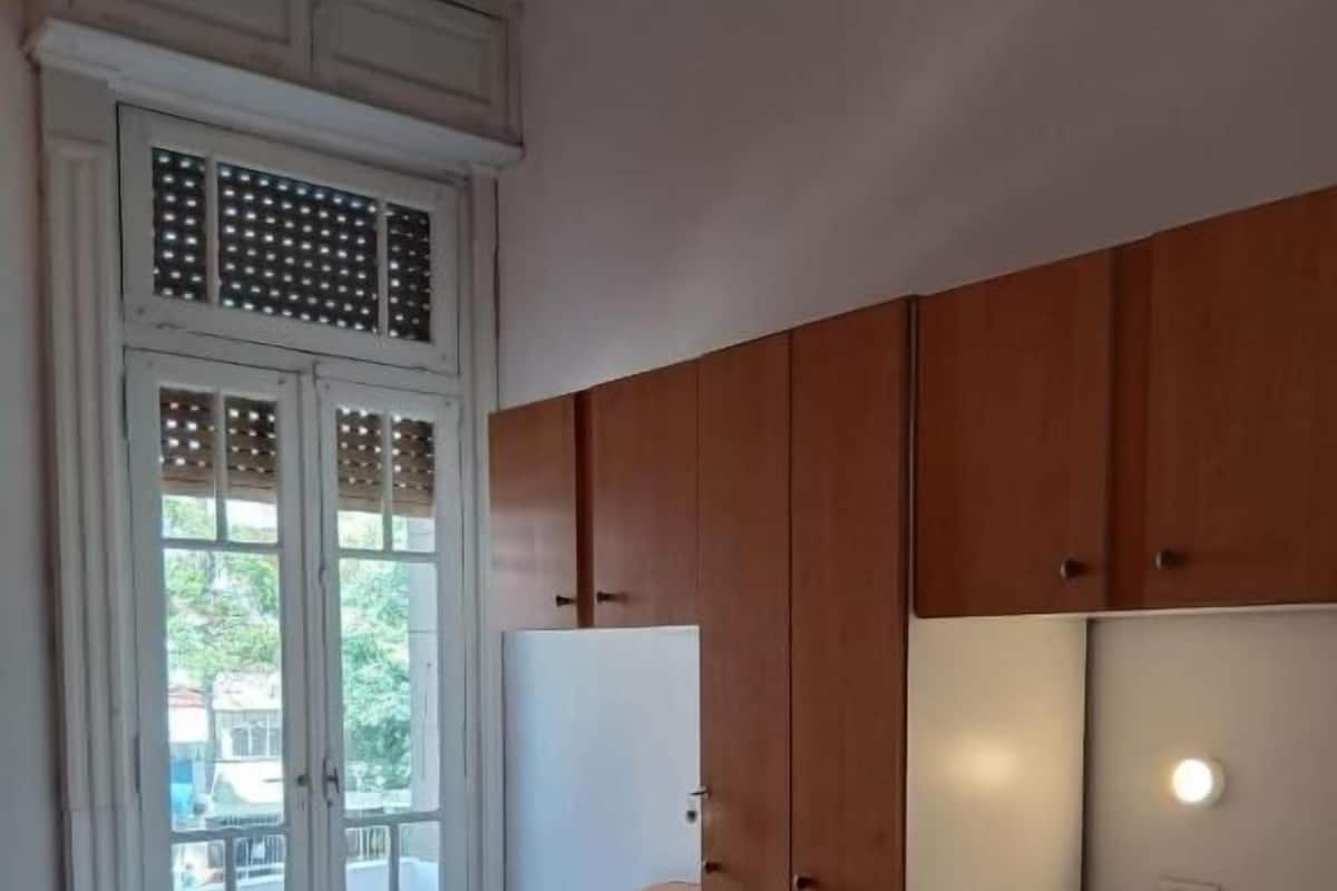 Una habitación con dos camas, armarios de madera, un guardarropa blanco y una ventana con vistas.