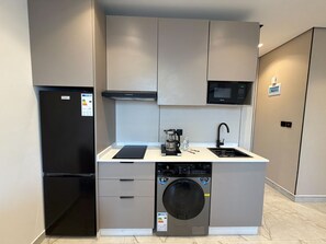 A compact kitchen with a built-in washer, a microwave, and a refrigerator. - 413 Tara-jre Jabal Al Lweibdeh With Stunning View (Amman)