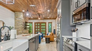Una cucina moderna con piani in granito, elettrodomestici in acciaio inossidabile e soffitto in legno.