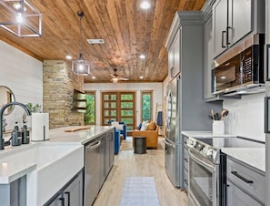 A modern kitchen with granite countertops, stainless steel appliances, and a wooden ceiling. - NEW! Tipi, Hot Tub, Arcade Games, Fire Pit, King Beds & Near Hochatown (Broken Bow)
