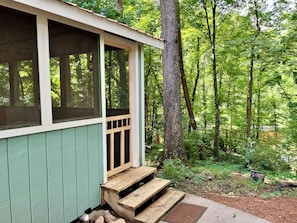 Eine kleine Hütte mit Veranda, umgeben von einem Wald.