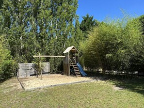 A playground with a slide and climbing structure, surrounded by trees and a sandy area. - LES EMBRUNS - VIELLE SAINT GIRONS (VIELLE SAINT GIRONS)