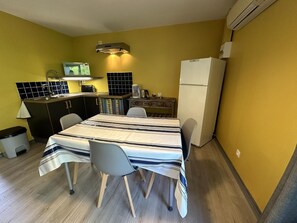 A compact kitchen with a dining table, chairs, a refrigerator, and a small countertop with a sink and stove. - LES EMBRUNS - VIELLE SAINT GIRONS (VIELLE SAINT GIRONS)