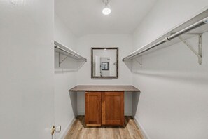 A narrow hallway with a wooden cabinet, a door, and a light fixture on the ceiling. - Cozy Colony Cottage (The Colony)