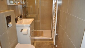 A bathroom with a toilet, sink, shower, and towel rack. - Studio Apartments City&style (Zagreb)