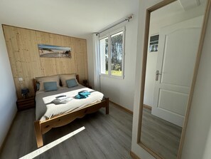 A bedroom with a wooden bed, a painting on the wall, a window with a view of trees, and a door. - BOIS FLOTTE - VIELLE SAINT GIRONS (VIELLE SAINT GIRONS)
