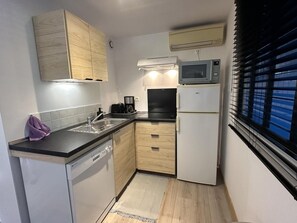 A compact kitchen with a dishwasher, a coffee maker, a refrigerator, and a window with blinds. - BOIS FLOTTE - VIELLE SAINT GIRONS (VIELLE SAINT GIRONS)