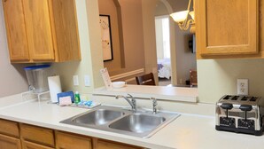 A kitchen with wooden cabinets, a double sink, a toaster, and a dishwasher. - Spacious 3-bedroom apartment, in the best community from Disney. (Kissimmee)