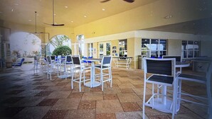 An indoor area with multiple tables and chairs, ceiling fans, and a tiled floor. - Spacious 3-bedroom apartment, in the best community from Disney. (Kissimmee)