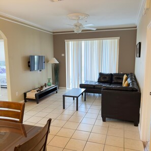Ein Wohnzimmer mit Sofa, Couchtisch, Fernseher und Deckenventilator.