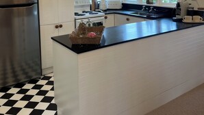 Een moderne keuken met een roestvrijstalen koelkast, een inbouwoven en een groot kookeiland met een zwart aanrecht.