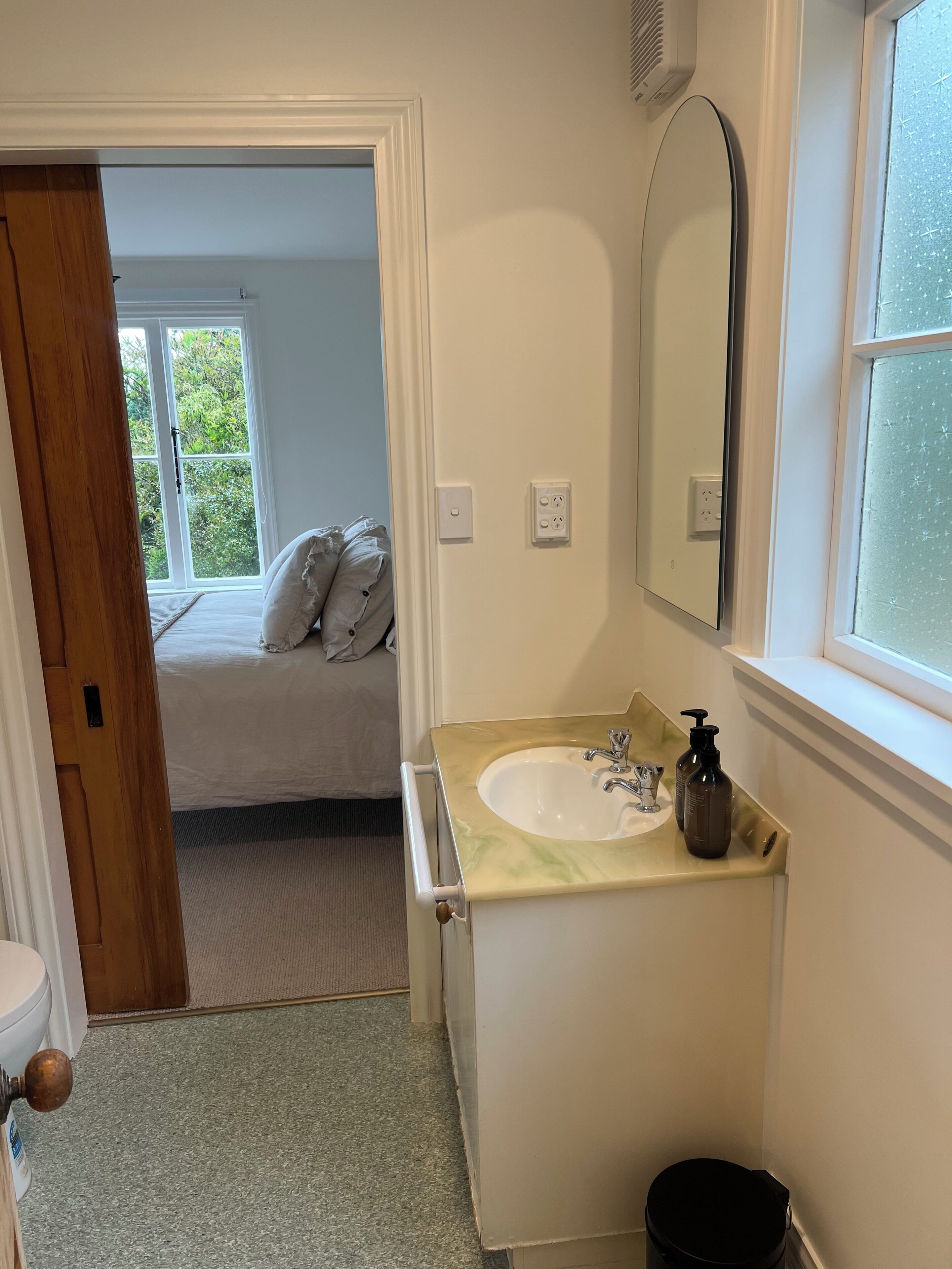 A bathroom with a sink, mirror, and window.