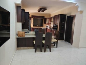 A compact kitchen with dark wood cabinets, a central island, and a dining area with chairs.
