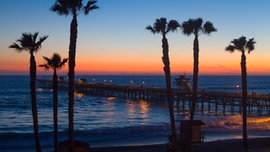 A pier extending into the ocean with palm trees and a lifeguard station.
