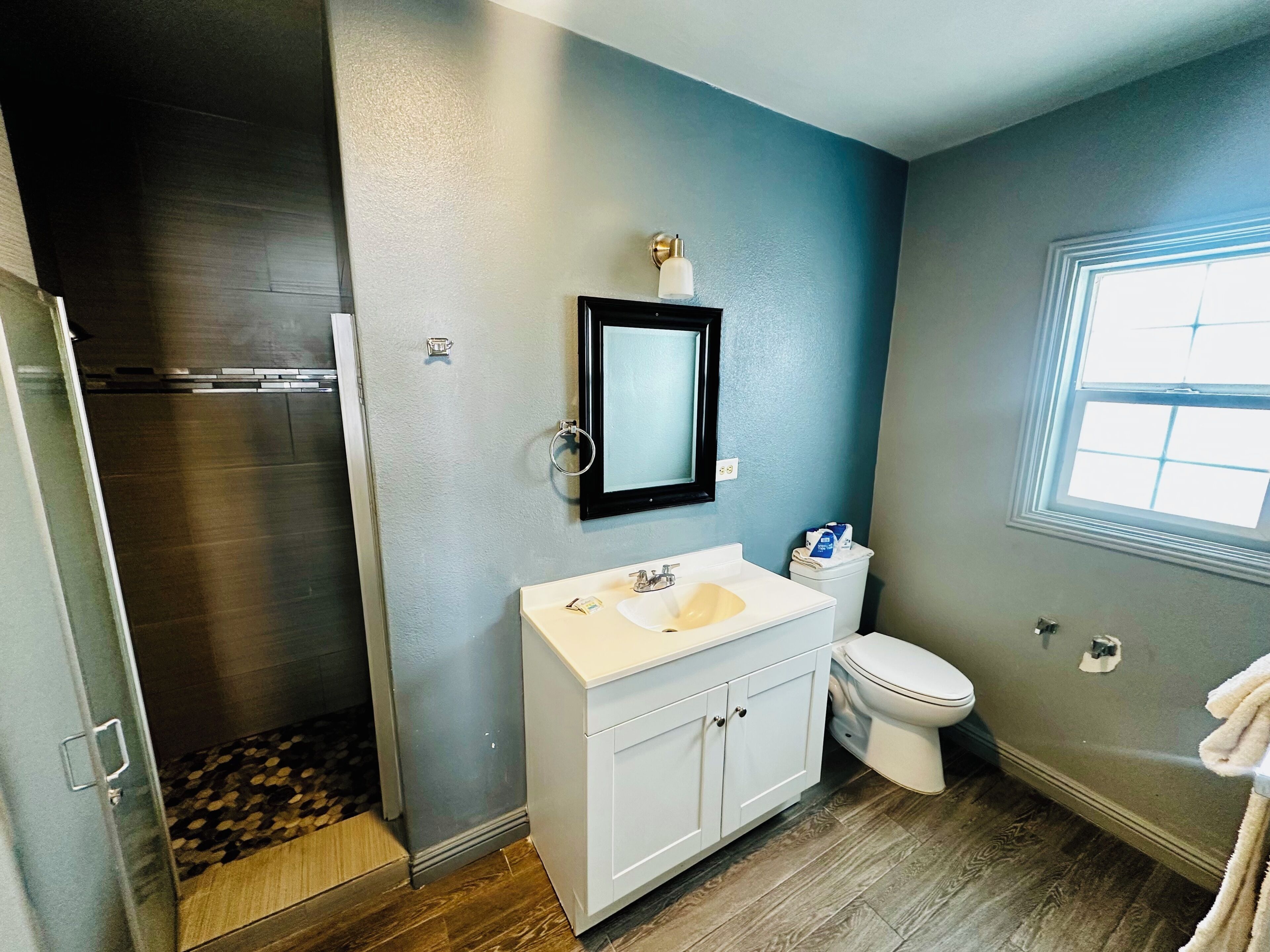 A bathroom with a shower, toilet, sink, and a window.