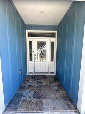 A blue exterior with a white door, a welcome mat, and a stone-tiled entrance. - Stay Salty Cottage (Foley)