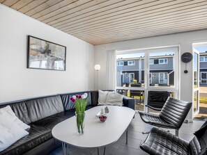Ein modernes Wohnzimmer mit einer Couch, einem Couchtisch und Blick auf die Nachbarhäuser.