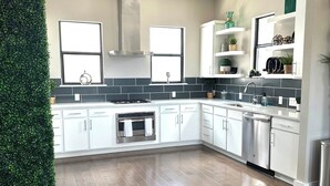 Una cocina moderna con armarios blancos, una campana extractora de acero inoxidable, horno empotrado y lavavajillas.