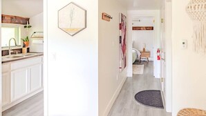 A modern kitchen with white cabinets, a wooden countertop, and a hexagonal wall art piece.