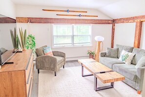Un salon chaleureux avec un canapé, un fauteuil, une table basse en bois et une lampe.