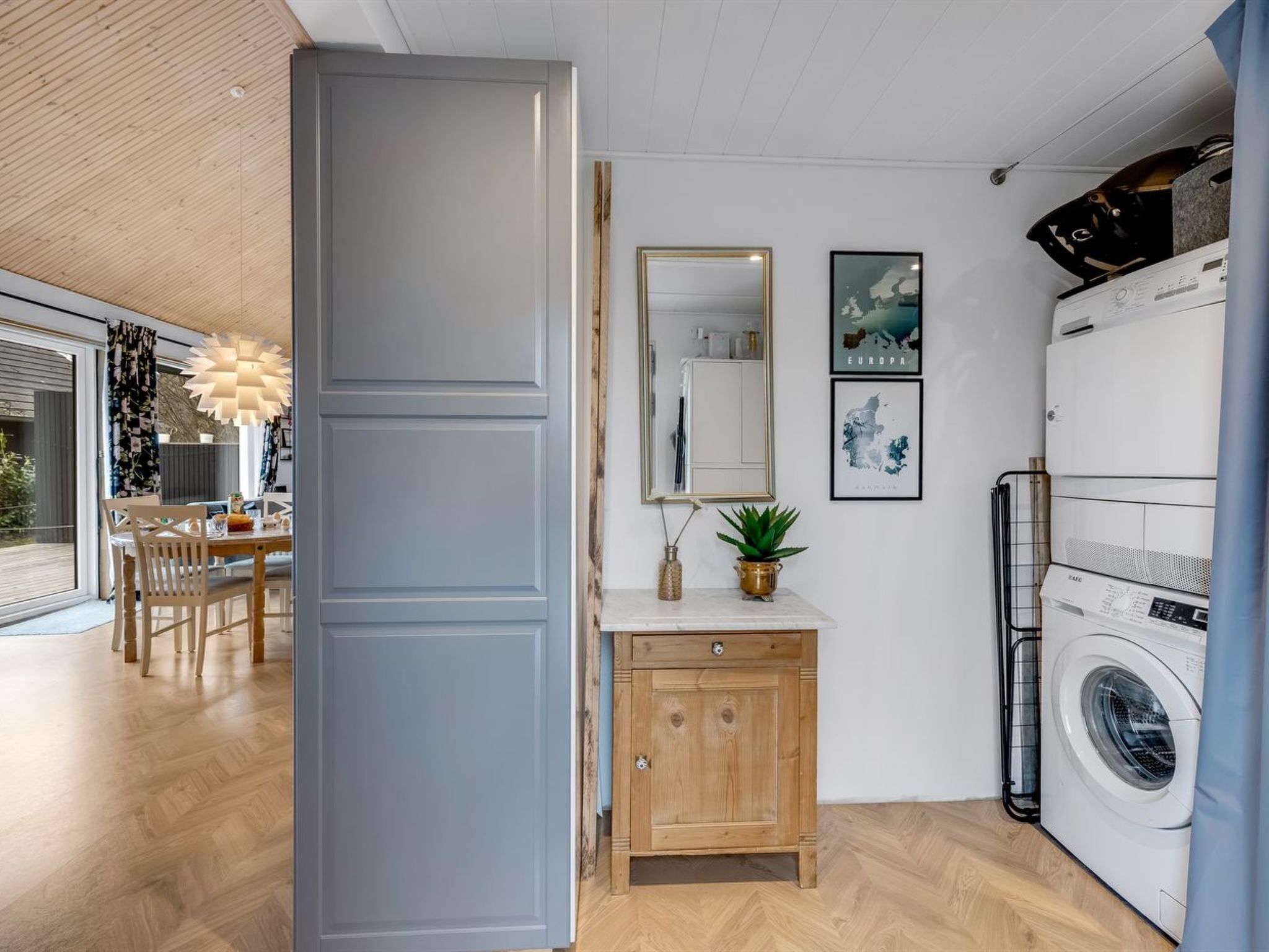 A modern kitchen with a built-in oven, a dining area with wooden chairs, and a large window.