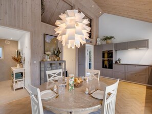 Eine moderne Küche mit grauen Schränken, einem eingebauten Backofen und einem Essbereich mit einem runden Tisch und Stühlen.