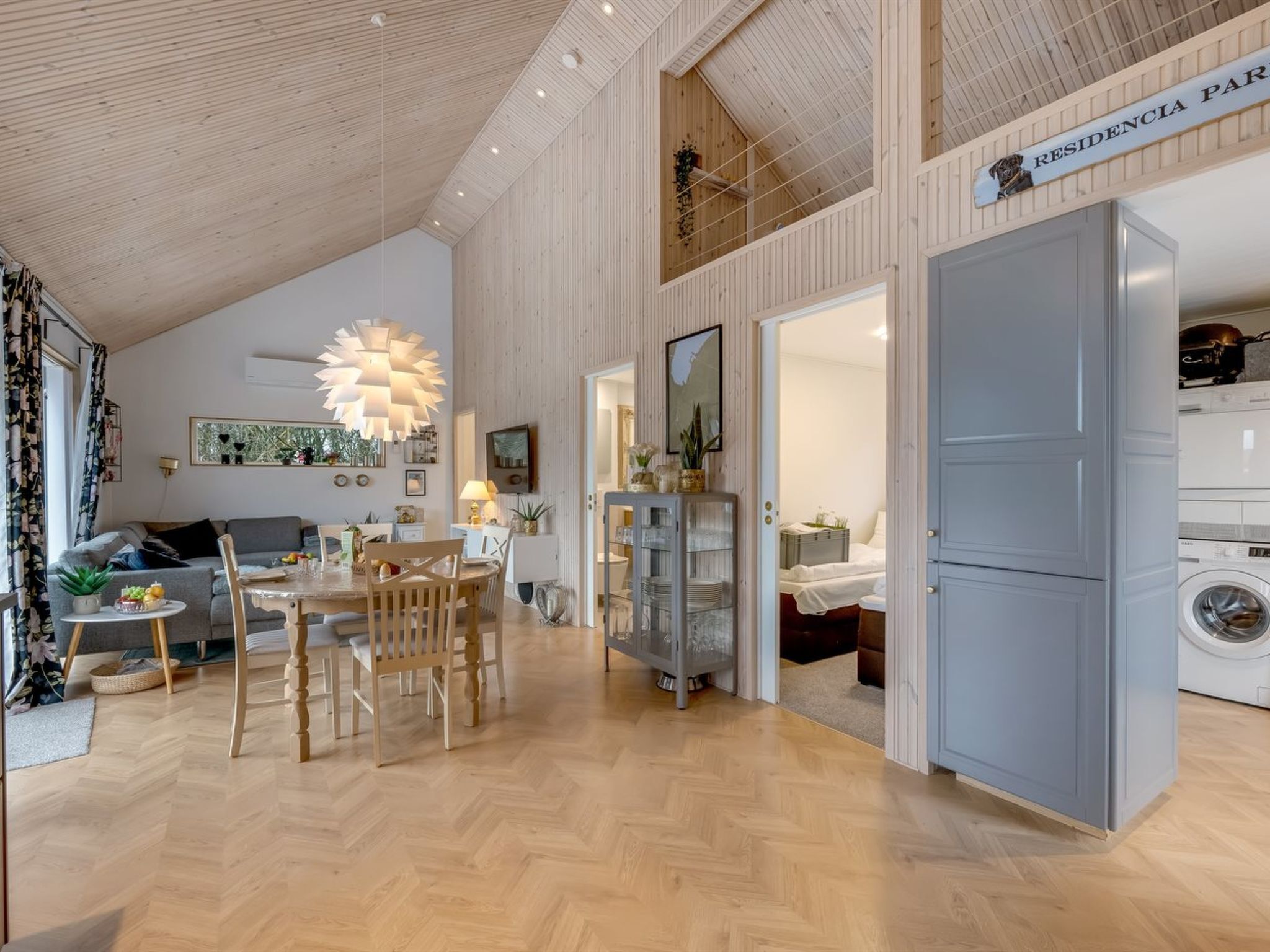 A modern interior with a dining area, kitchen, and a visible laundry room.