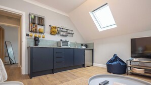Een moderne keuken met dakraam, een eethoek met tafel en stoelen, en een woonkamer met televisie.