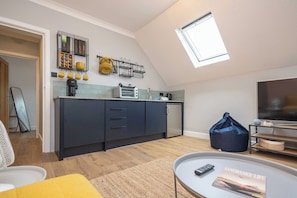 A modern kitchen with a skylight, a dining area with a table and chairs, and a living room with a TV.
