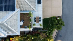 An aerial view of a rooftop patio with a dining table and chairs, surrounded by potted plants and a small seating area. - Chelsea Poolside and Tennis (Nelson Bay)