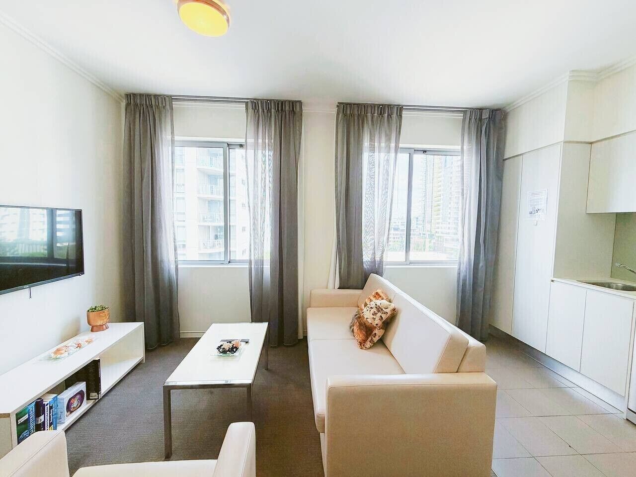 Un salon moderne comprenant un canapé, une table basse, un téléviseur et un coin cuisine.