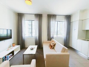 Ein modernes Wohnzimmer mit einer Couch, einem Couchtisch, einem Fernseher und einer Küchenzeile.