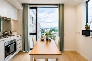 Eine moderne Küche mit Essbereich, großen Fenstern und Blick auf die Stadtlandschaft.