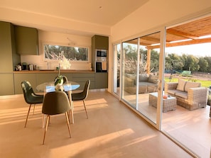 A modern kitchen with a dining area, sliding glass doors leading to an outdoor seating area.