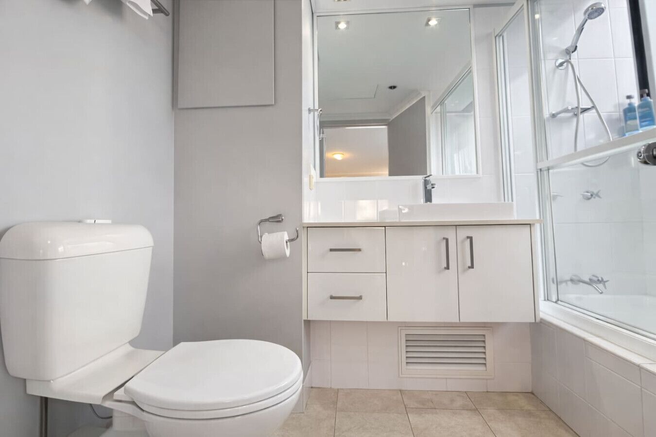 A modern bathroom with a toilet, sink, mirror, and shower.