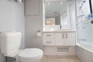Ein modernes Badezimmer mit Toilette, Waschbecken, Spiegel und Dusche.