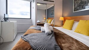 Een hotelkamer met een bed, een bureau, een stoel, een raam en een schilderij aan de muur.