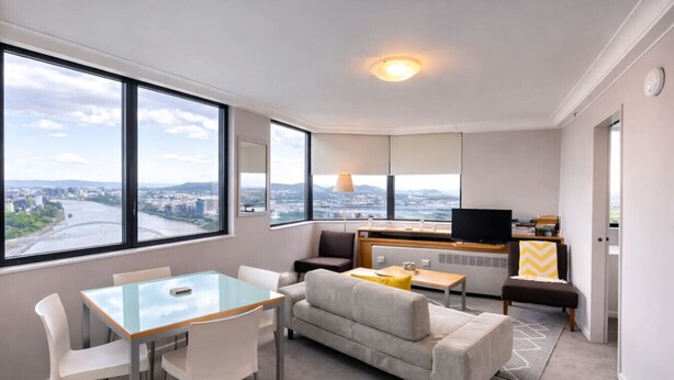 Een moderne woonkamer met een glazen tafel, bank en televisie.