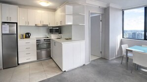 Een moderne keuken met witte kastjes, roestvrijstalen apparatuur, een magnetron en een eethoek met een tafel en stoelen.