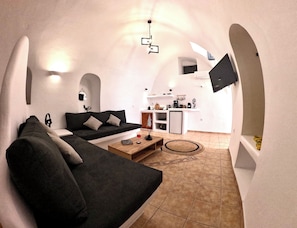 Ein kompakter Wohnbereich mit Sofa, Couchtisch und Küchenzeile, inklusive Fernseher.